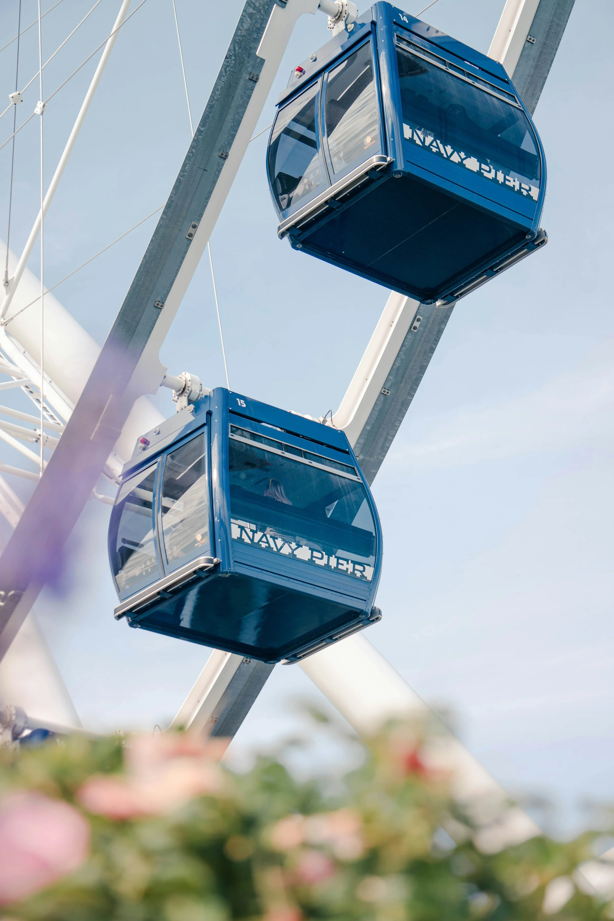 Close-up of the Navy Pier Ferris wheel's blue gondolas labeled 'NAVY' against a clear sky, in Chicago, Illinois.