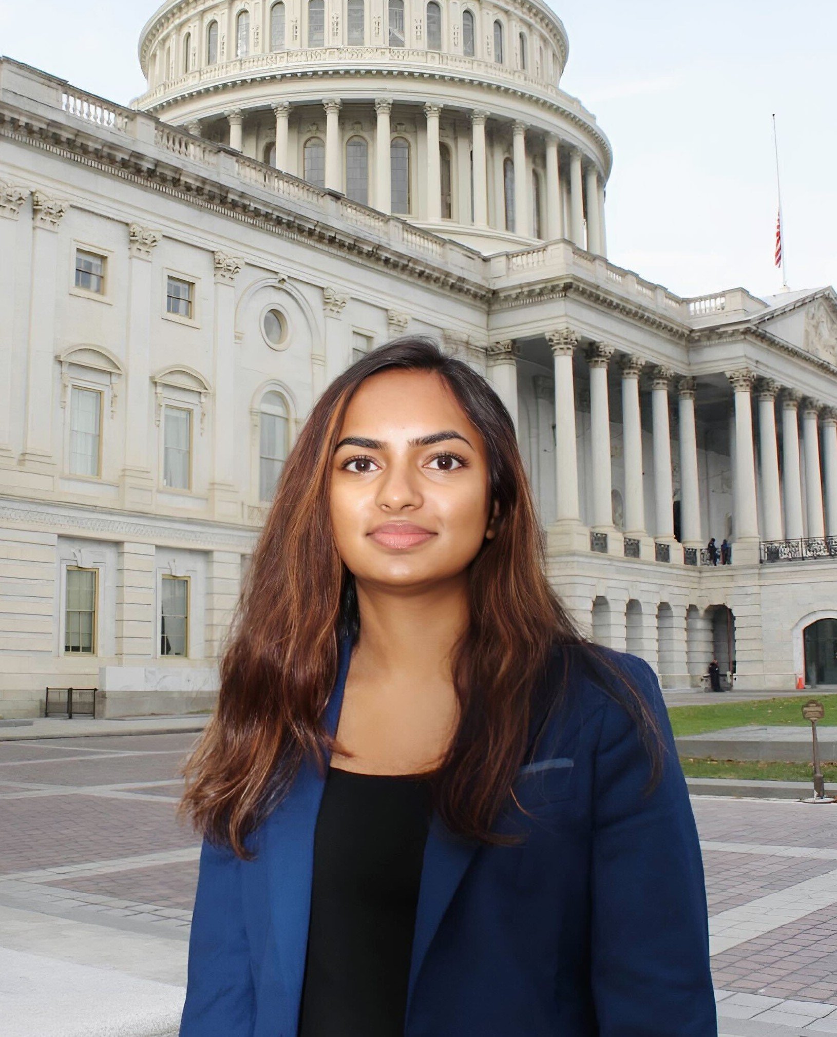 A woman with long brown hair and a friendly expression standing in front of the U.S. Capitol building in Washington, D.C.