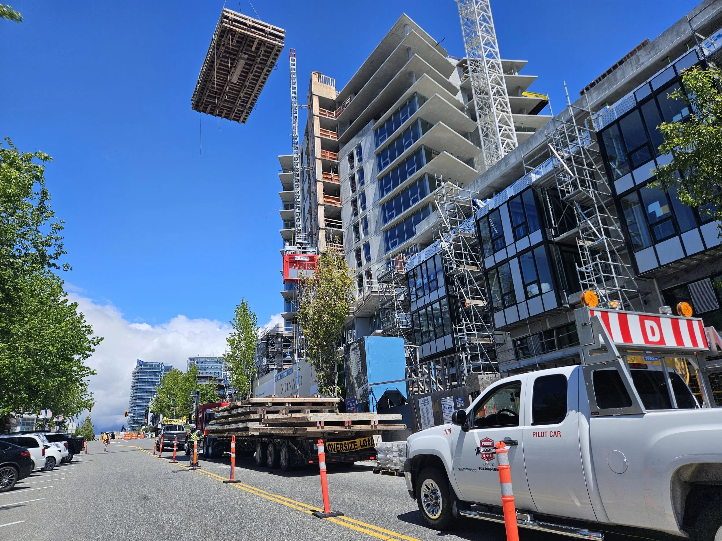 crane lifting wood on jobsite above pilot truck