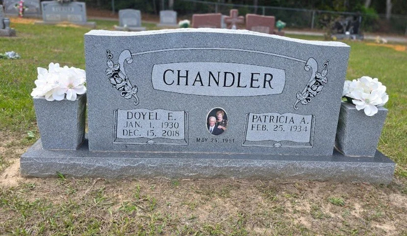 Gravestone with the surname Chandler, featuring photos, floral arrangements, and the names Doyel F. and Patricia A.