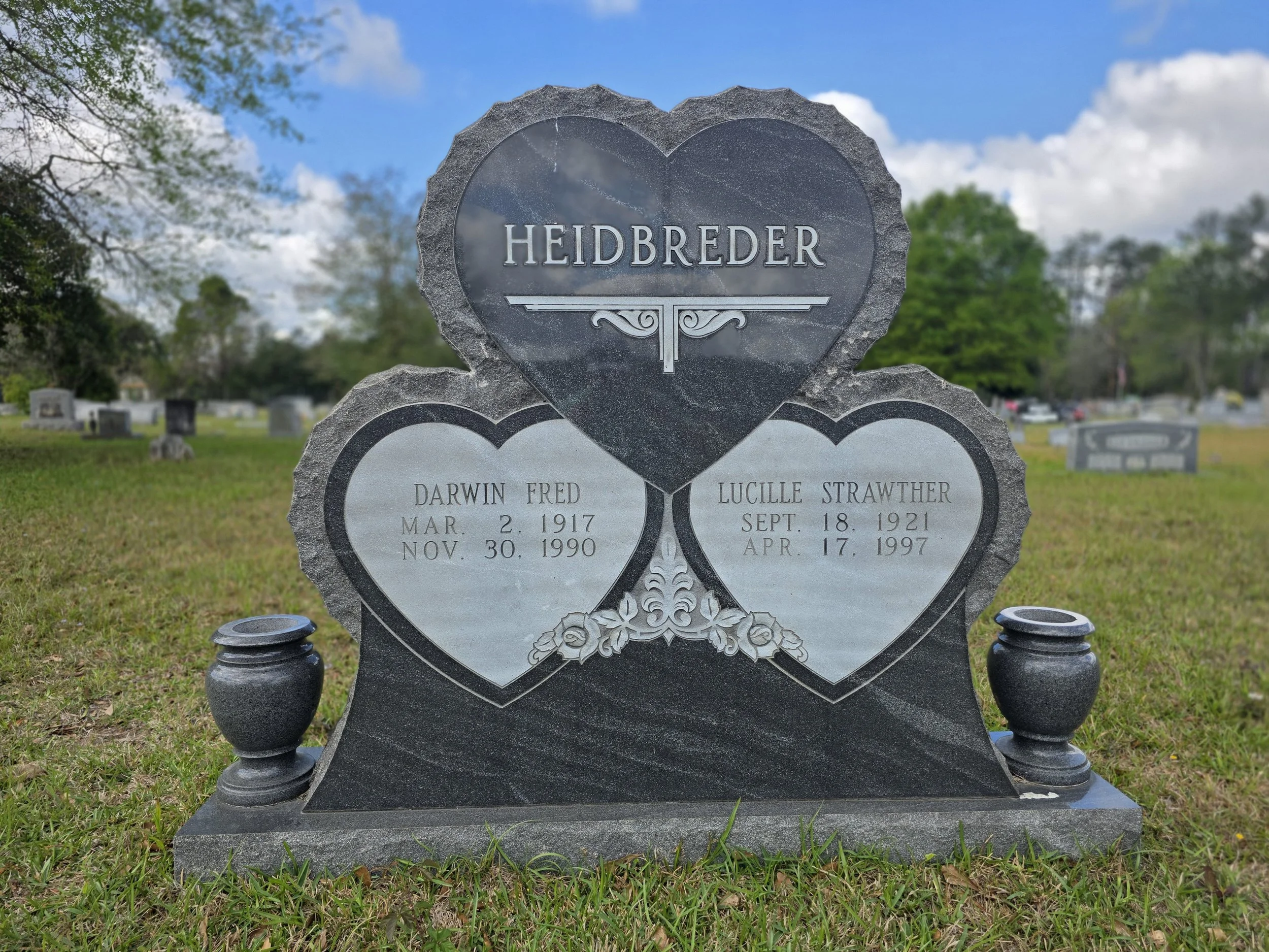 A family tombstone with three hearts in a cemetery.