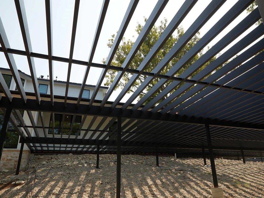 Looking up through a Fortress Evolution steel deck frame, black steel joists on beams and posts, before the surface goes on