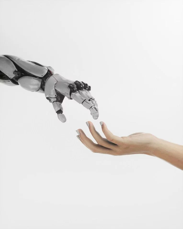 A robotic hand reaching out to touch a human hand against a plain white background.