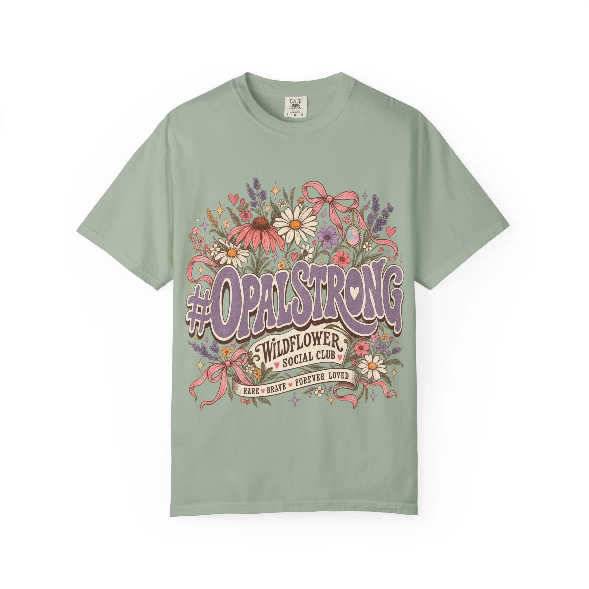 This heavyweight garment-dyed tee brings quiet confidence and warm nostalgia to everyday wear. Hand-drawn wildflowers and soft ribbon swirls frame a bold, vintage-inspired wordmark that reads like a rallying cry—gentle but unshakable. The dye-after-c
