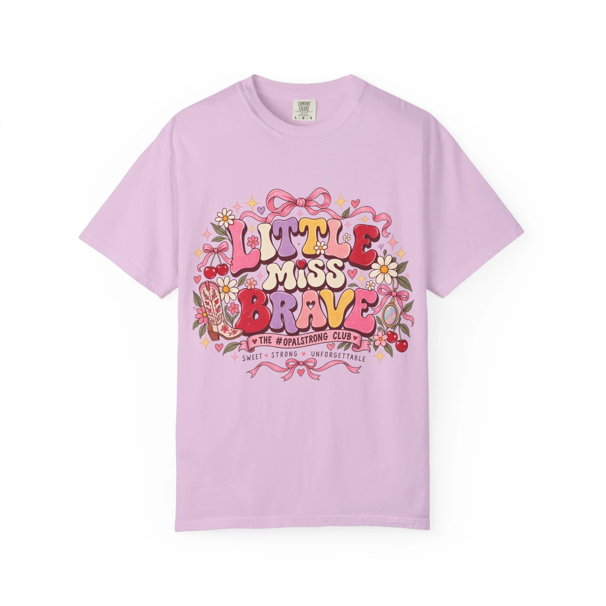 A soft, garment-dyed tee that feels lived-in from the first wear. Warm, vintage-inspired lettering reads “Little Miss Brave” surrounded by hand-drawn florals, hearts, and playful bows — a cheerful, retro look with a gentle, empowering message. The he
