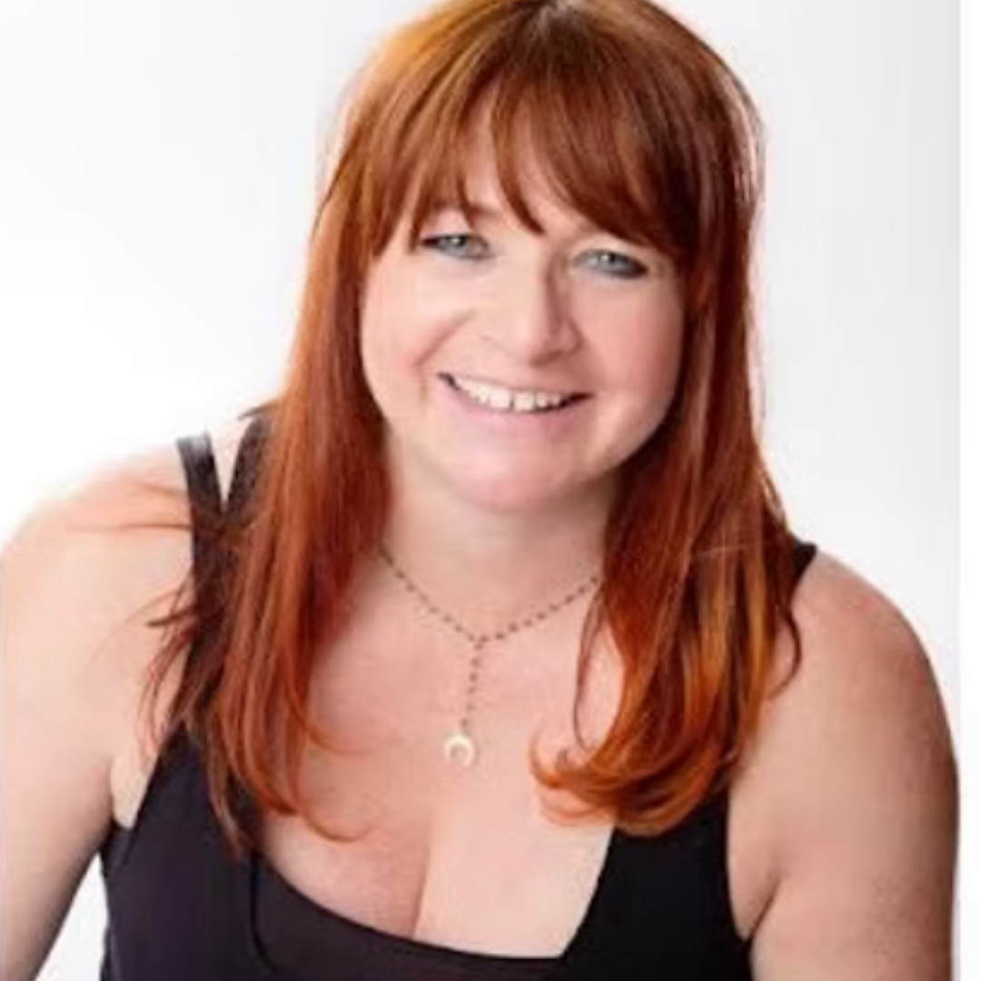 Michelle Mann-Donegan, guest yoga teacher, Smiling with long red hair wearing a black sleeveless top and a necklace with a crescent moon pendant against a white background.