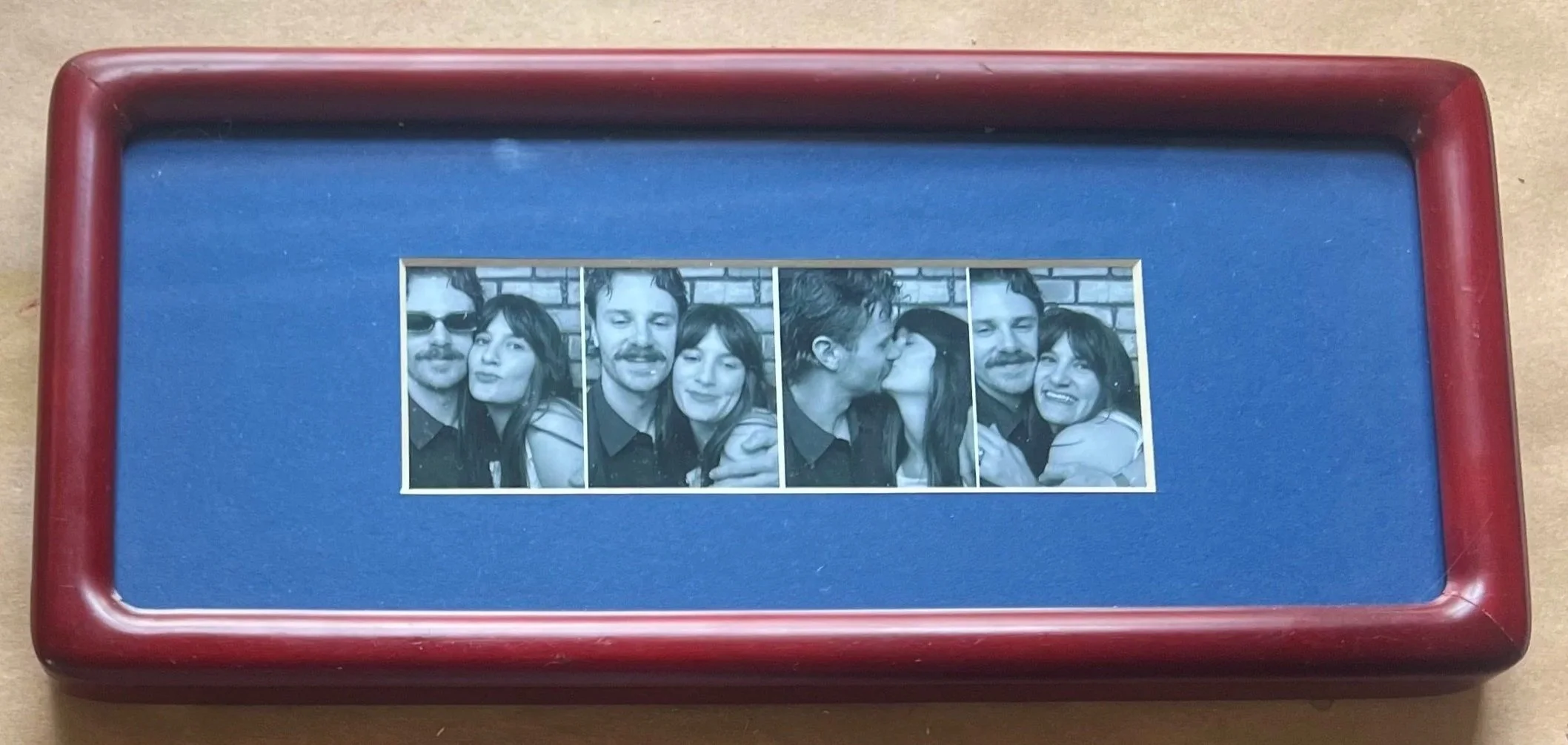 A photo strip with four black-and-white pictures of a couple showing various affectionate poses.