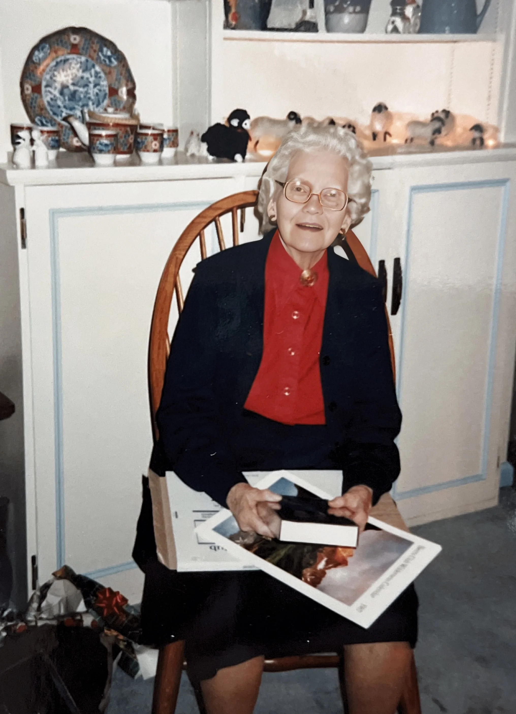 Grandma Benedict holding old family photos, a legacy of love and faith