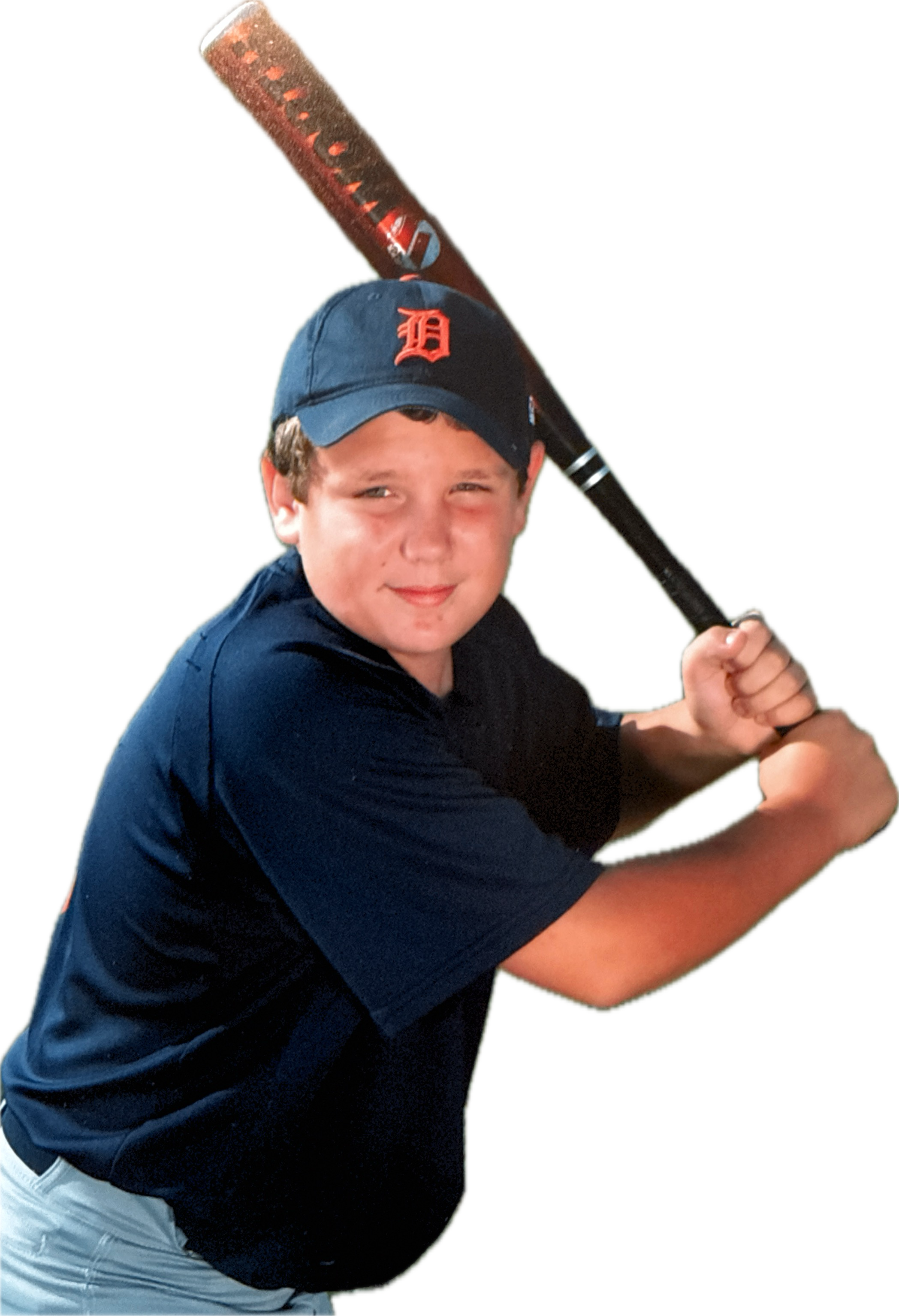 A young boy with a dark blue baseball cap with a red 'D' logo, wearing a dark blue shirt, holding a baseball bat over his shoulder, smiling slightly, with a black background.