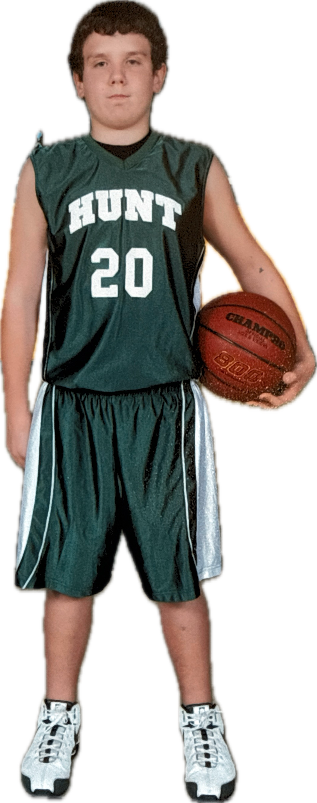 Young boy in a green basketball uniform with the number 20 and the word 'HUNT' on it, holding a basketball, wearing athletic shoes.