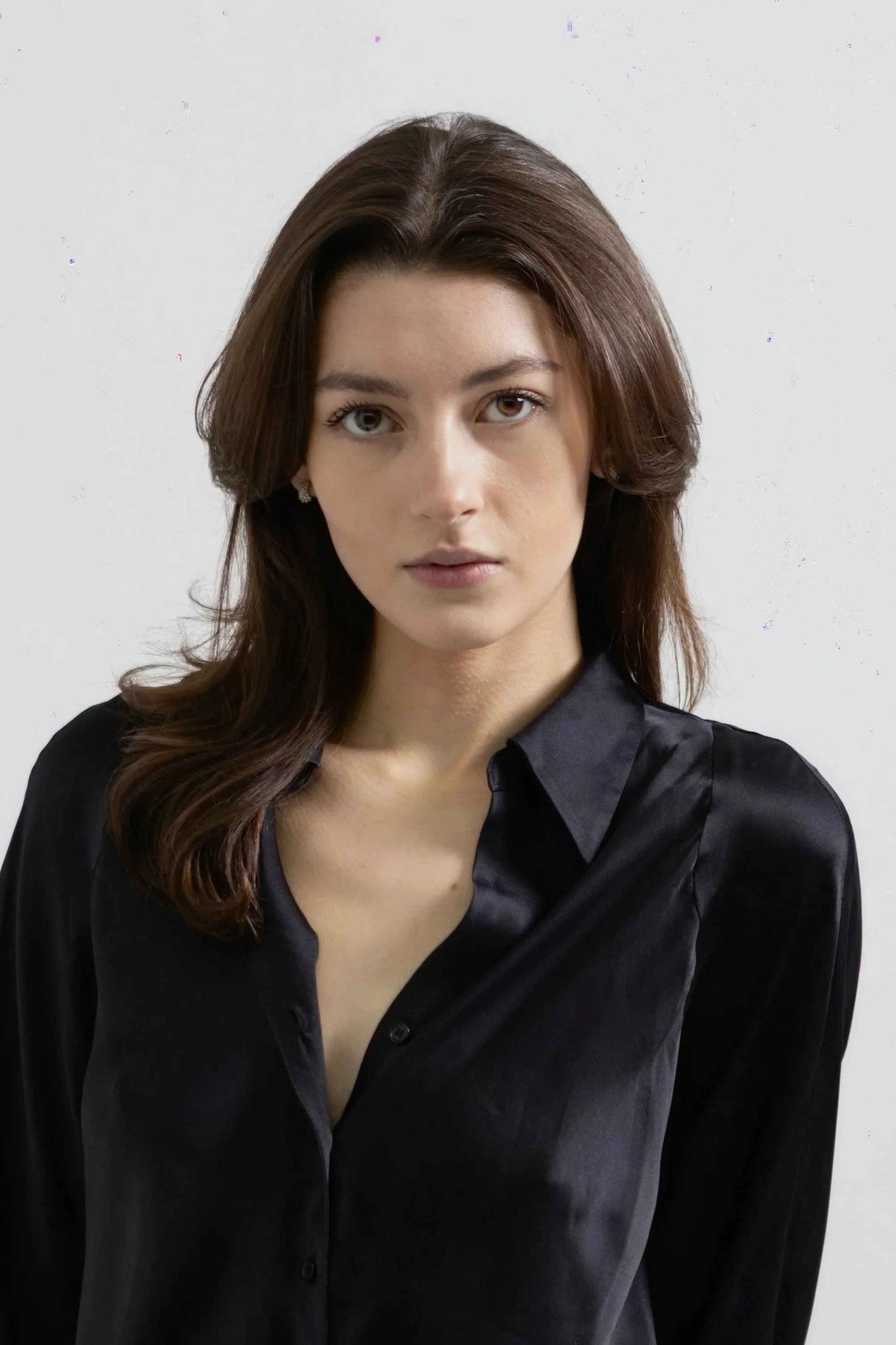 Portrait of a young woman with brown hair wearing a black silk blouse.
