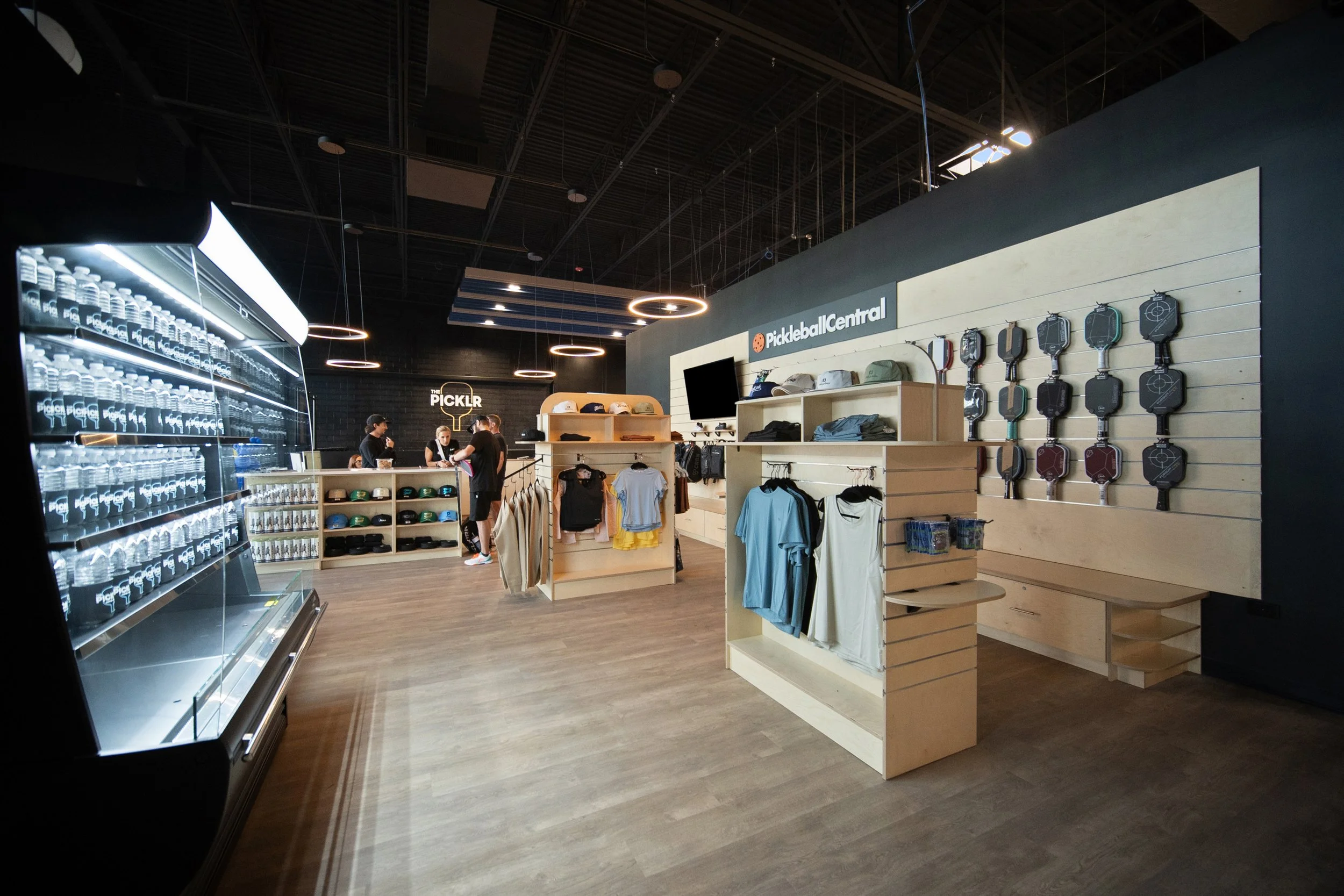 Inside a retail store featuring sunglasses, clothing, and pickleball equipment on display.