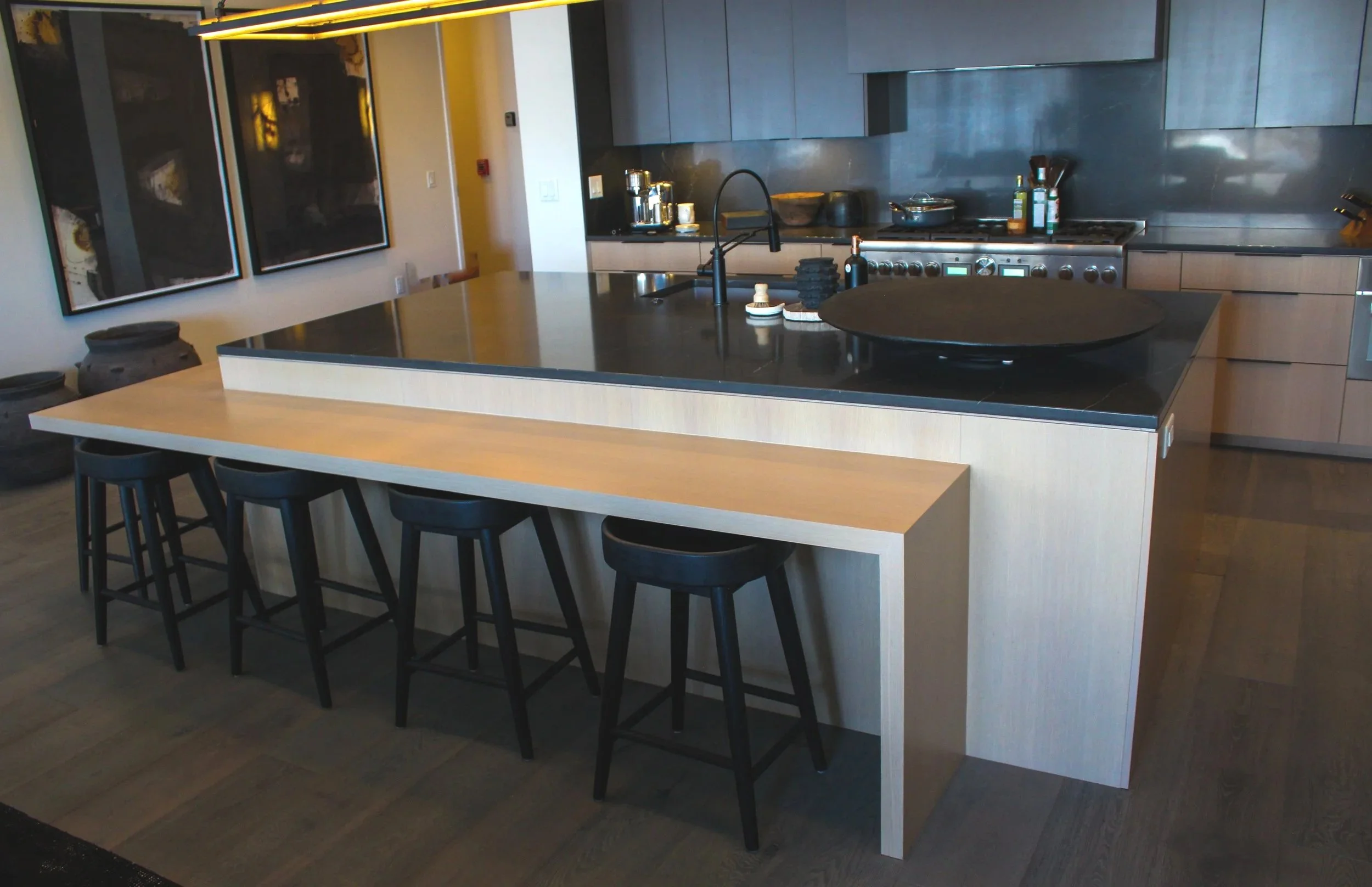 Modern kitchen with a large island counter, black countertop, and art pieces on the wall.