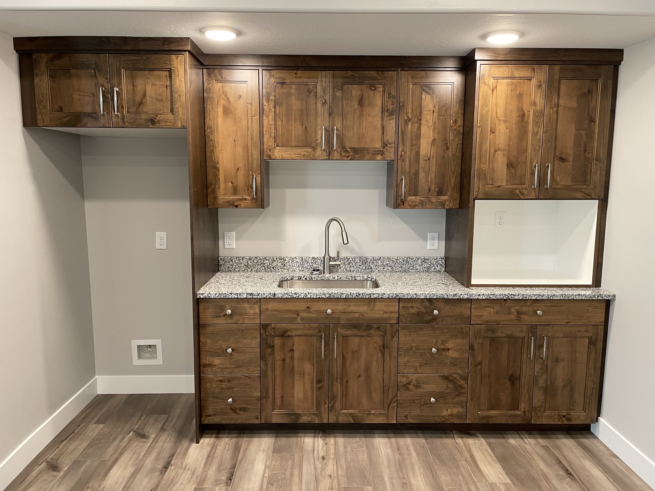 Kitchen cabinets with wood finish and a granite countertop with a sink.