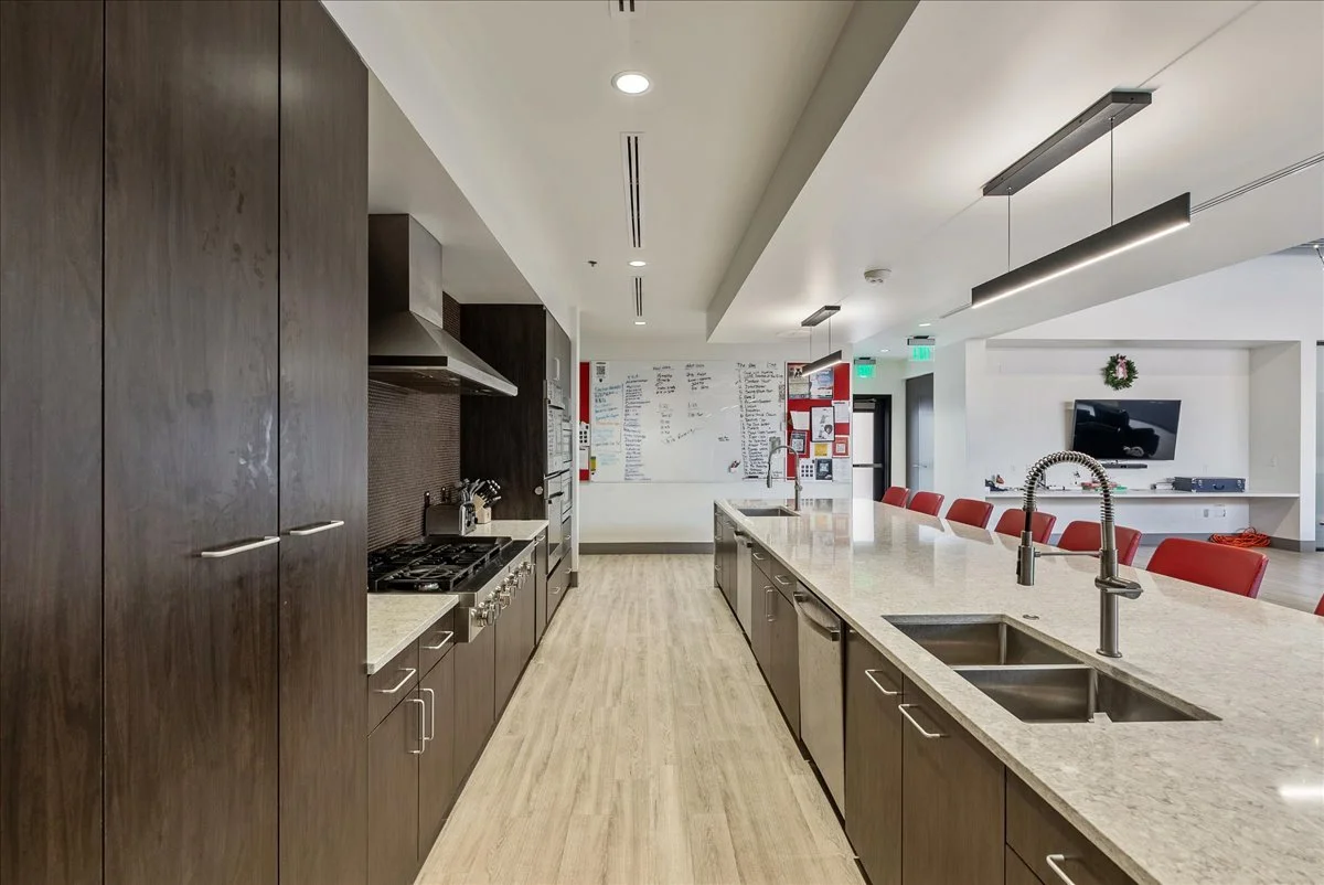 Modern kitchen with dark wood cabinets, stainless steel appliances, and a large light-colored countertop island with a double sink.