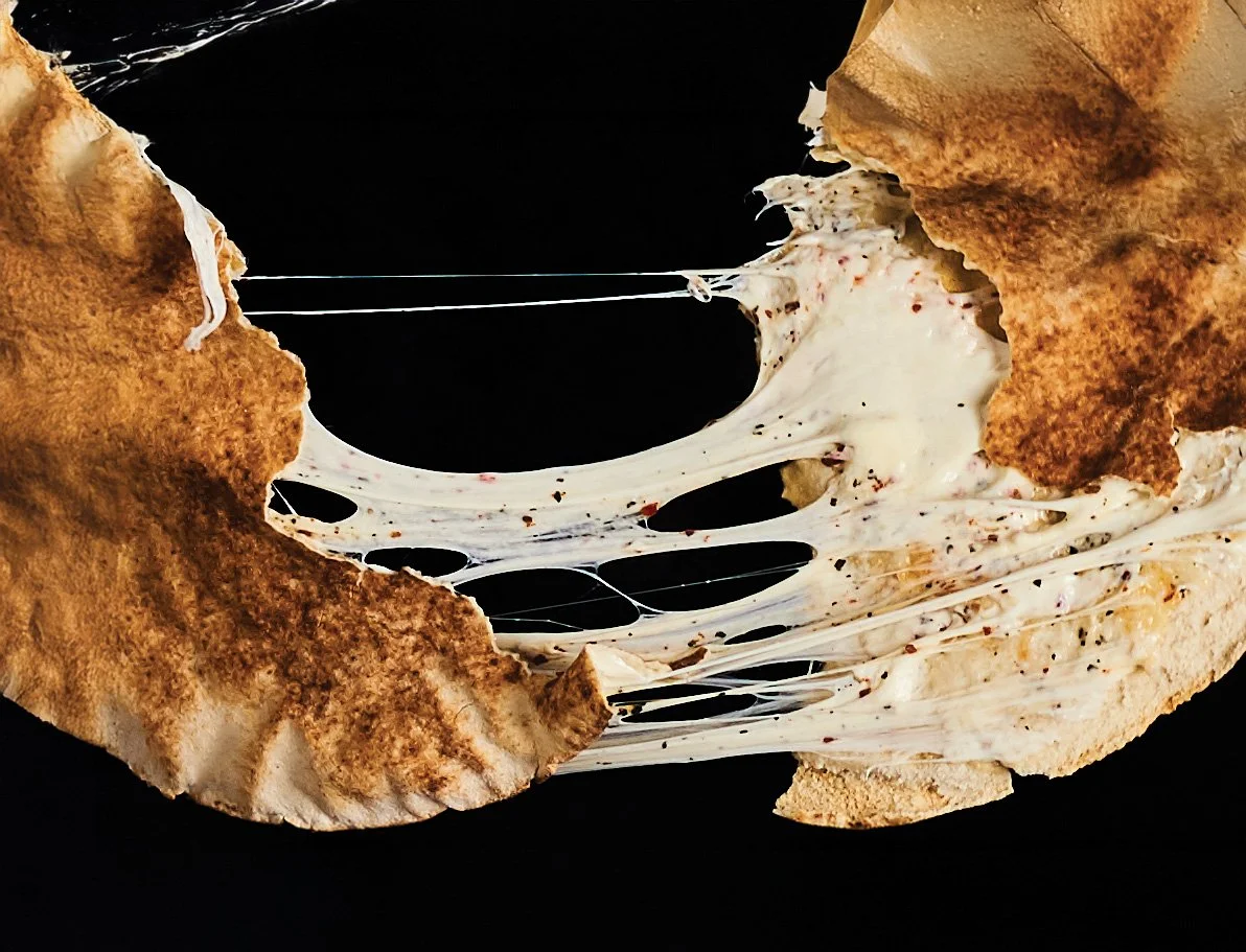 A close-up of Syrian grilled cheese sandwich. Jibneh Syrian cheese pulling apart on black background.