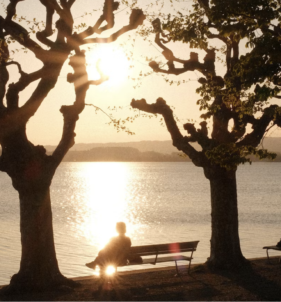A man sitting on a bench looking over water.