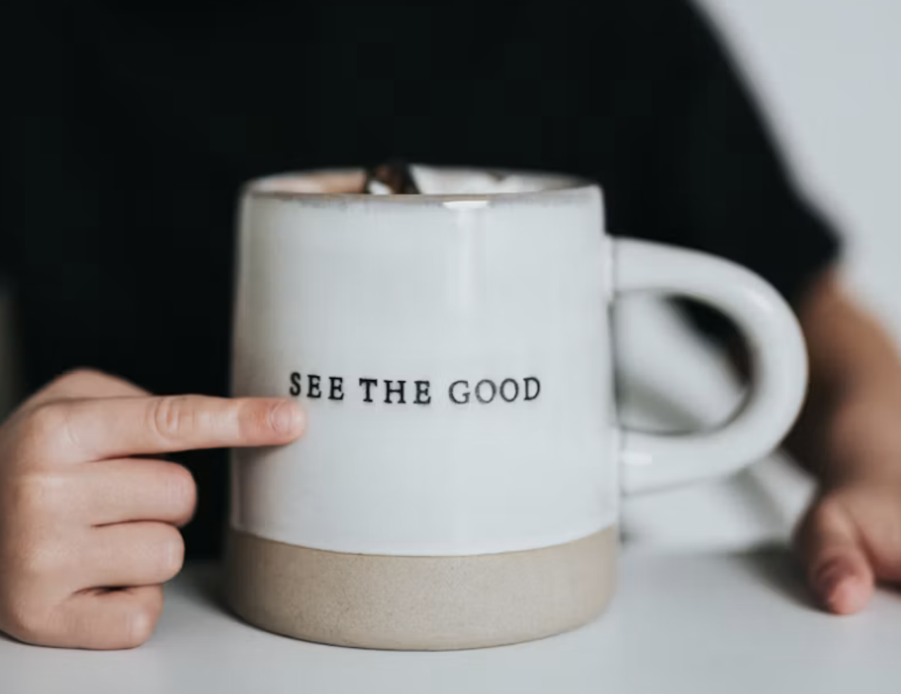 A boy pointing to a copy mug that says SEE THE GOOD