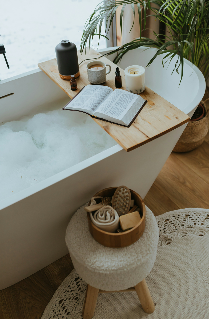 A relaxing bathtub with coffee, a candle and a book.