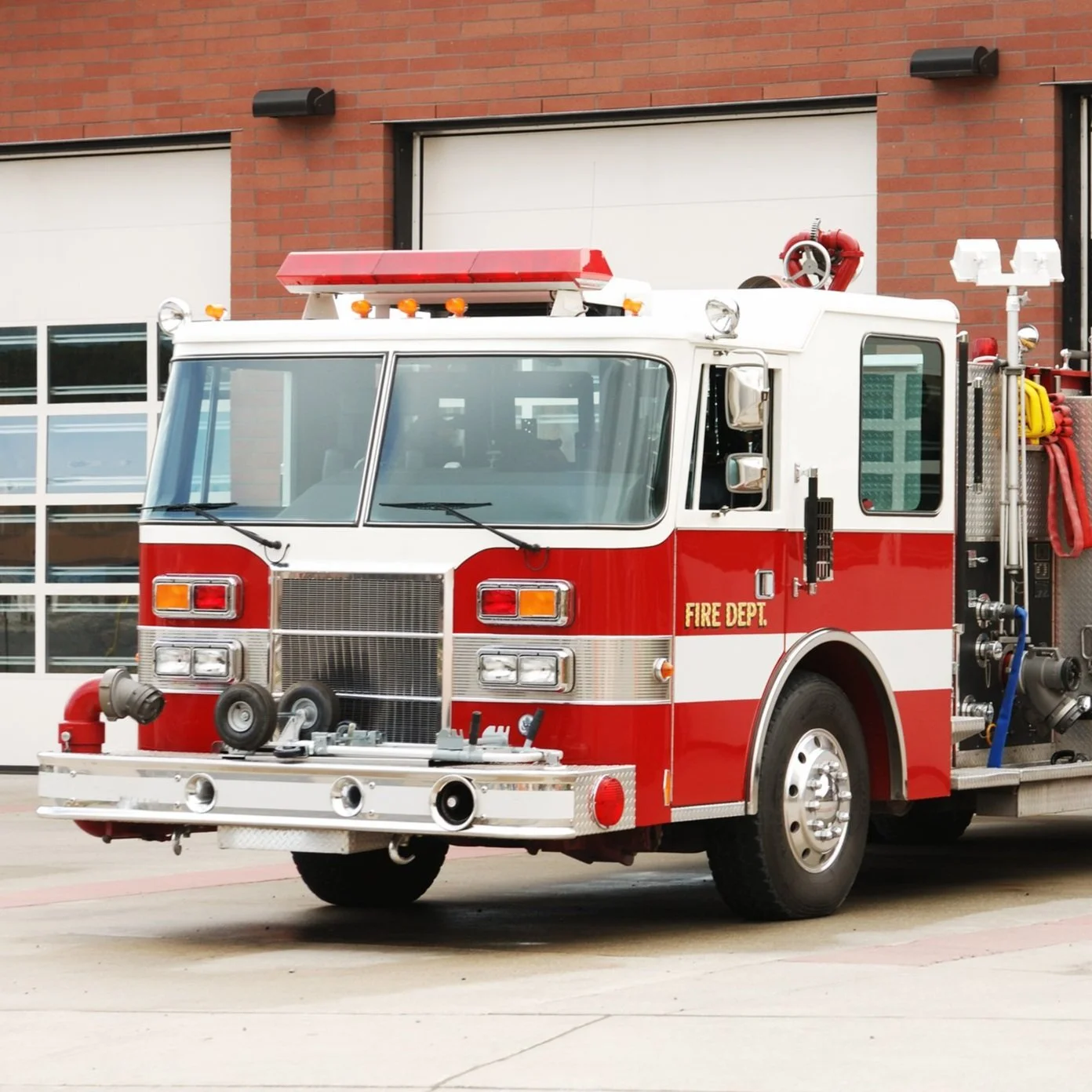 Red and white fire truck parked in front of a brick building.