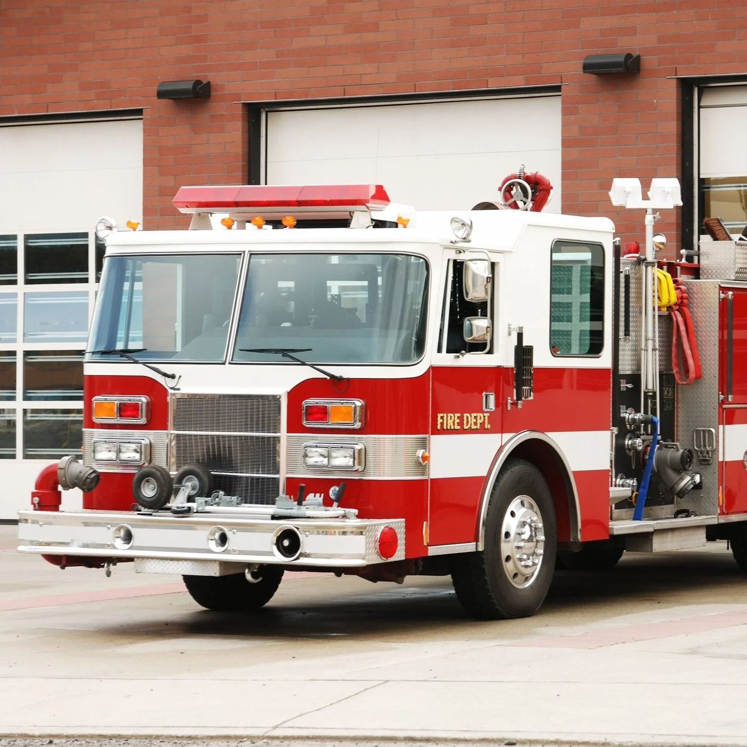 Red and white fire truck parked outside a building with brick walls and large windows.