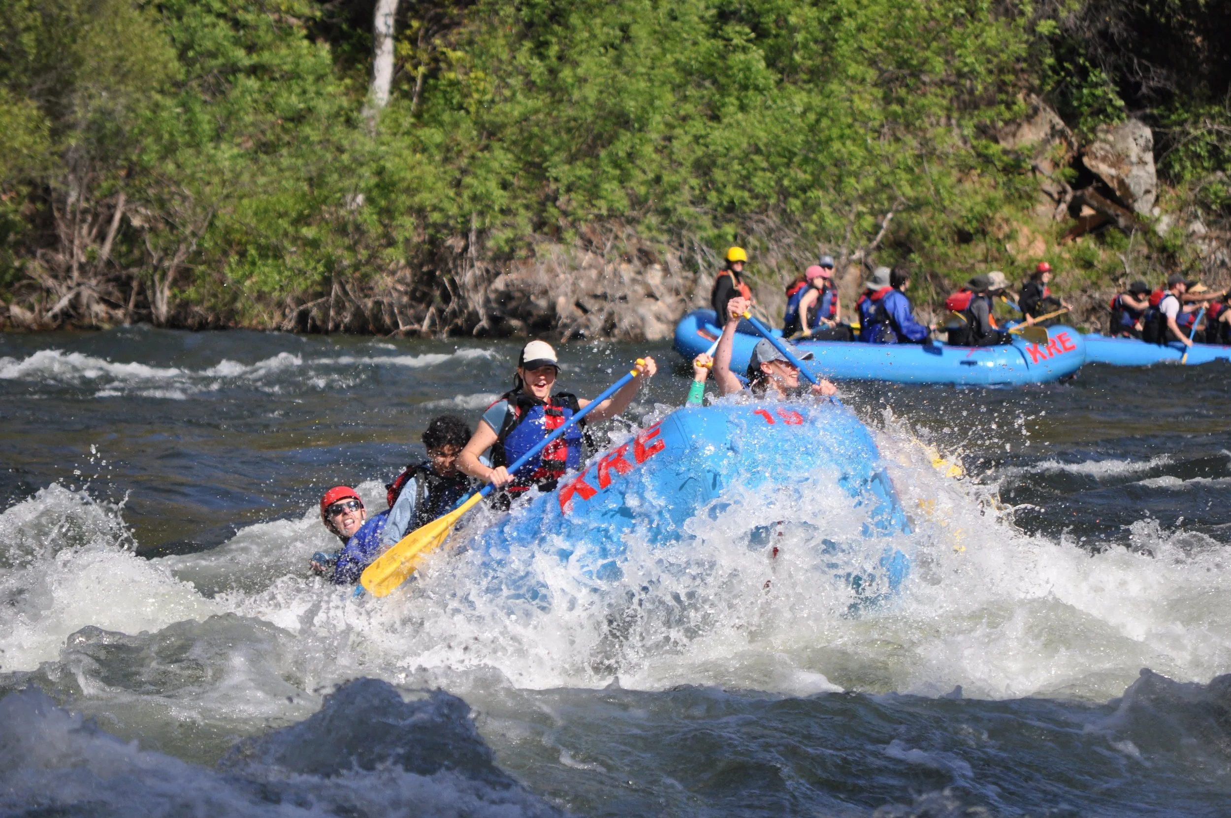 Group of people white-water rafting on a river.