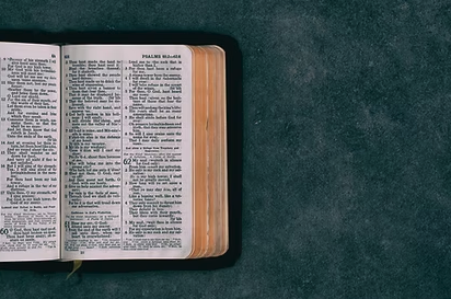 Open Bible with highlighted text on the left page, resting on a dark surface.