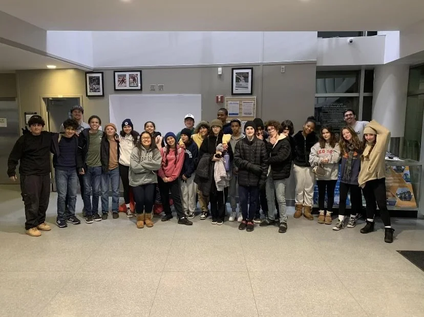 Group of children and teenagers standing together in a hallway, posing for a photo.