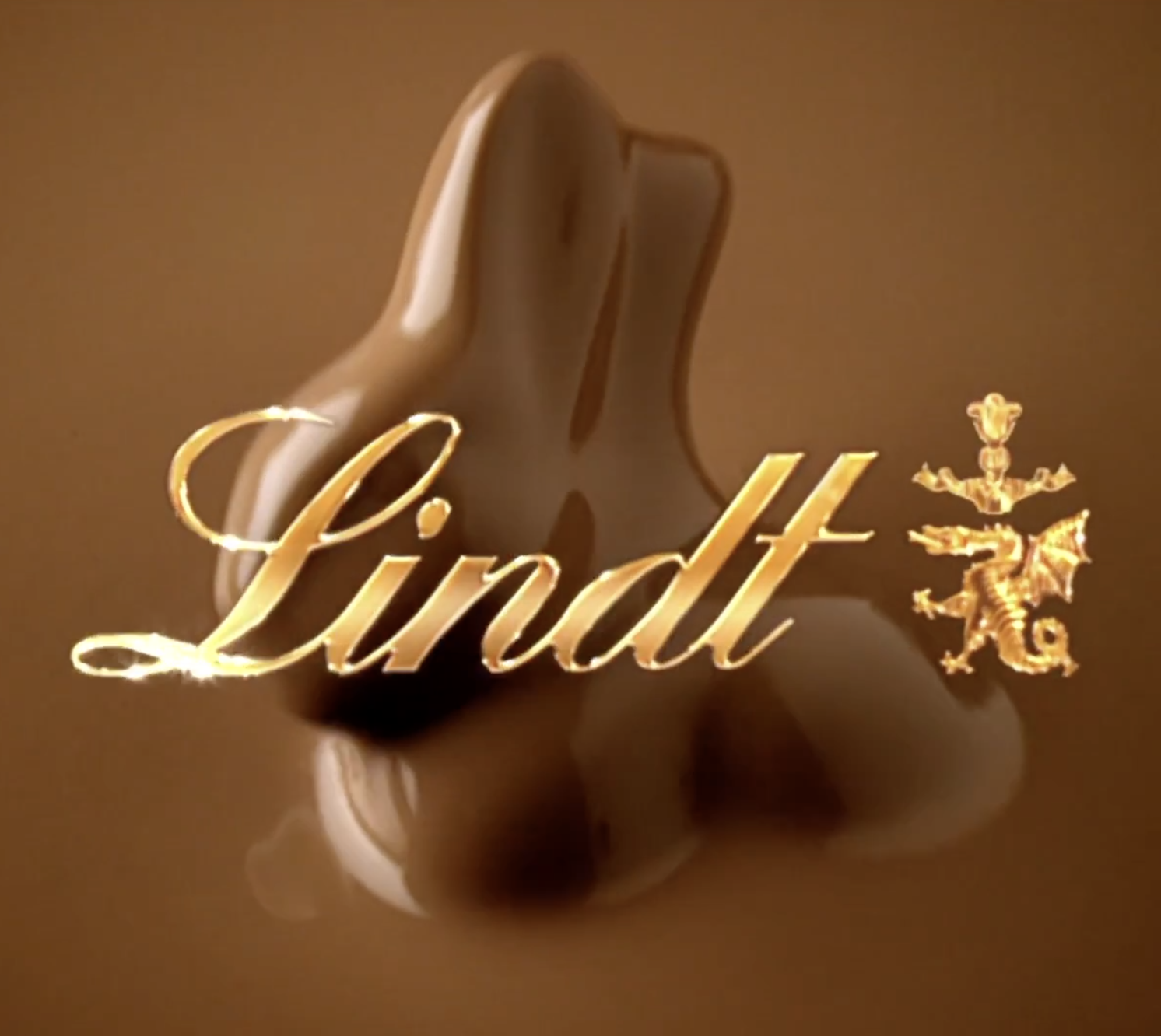 A luxury lipstick container with the word 'Lindt' in gold script and a gold dragon emblem, reflected on a brown surface.