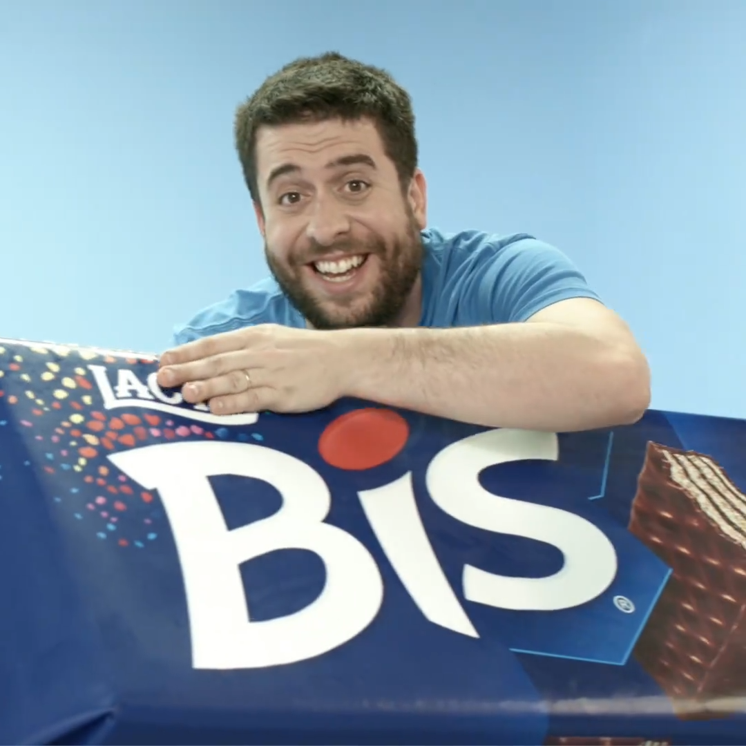 A man with a beard smiling and resting his head on a large blue box of Lay's Biscuit cookies.