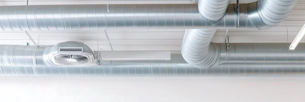 Ceiling with large metallic air ducts and an air vent in an industrial or commercial building.
