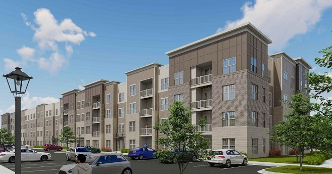 A modern multi-story apartment complex with balconies, parking lot in front, and trees. Clear blue sky.