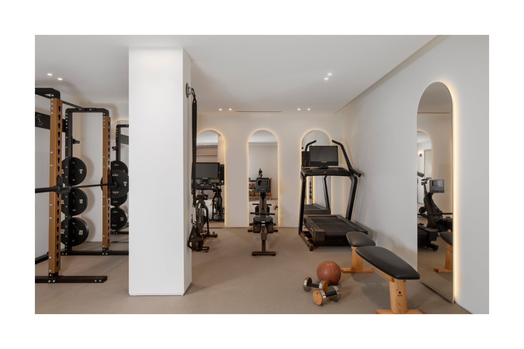 Modern home gym with weight racks, cardio equipment, benches, and a small exercise ball.