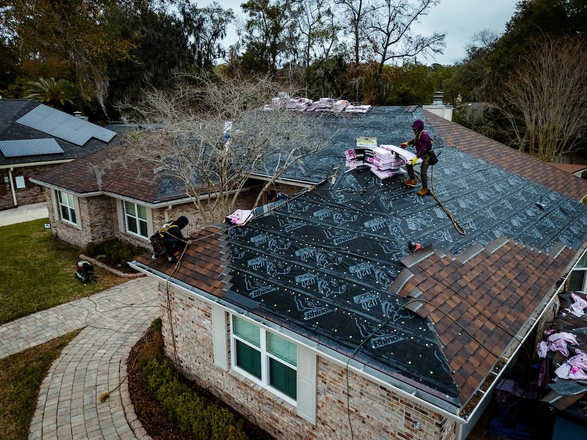 Professional roofing contractors installing architectural shingles on a residential home in Northeast Florida.