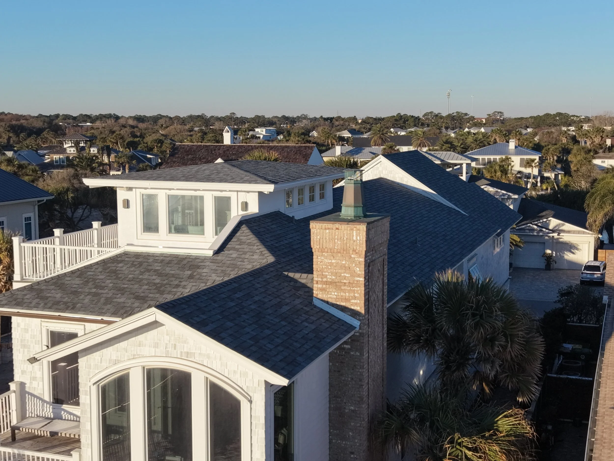 Premium roof replacement for a large white multi-story home with a modern design.