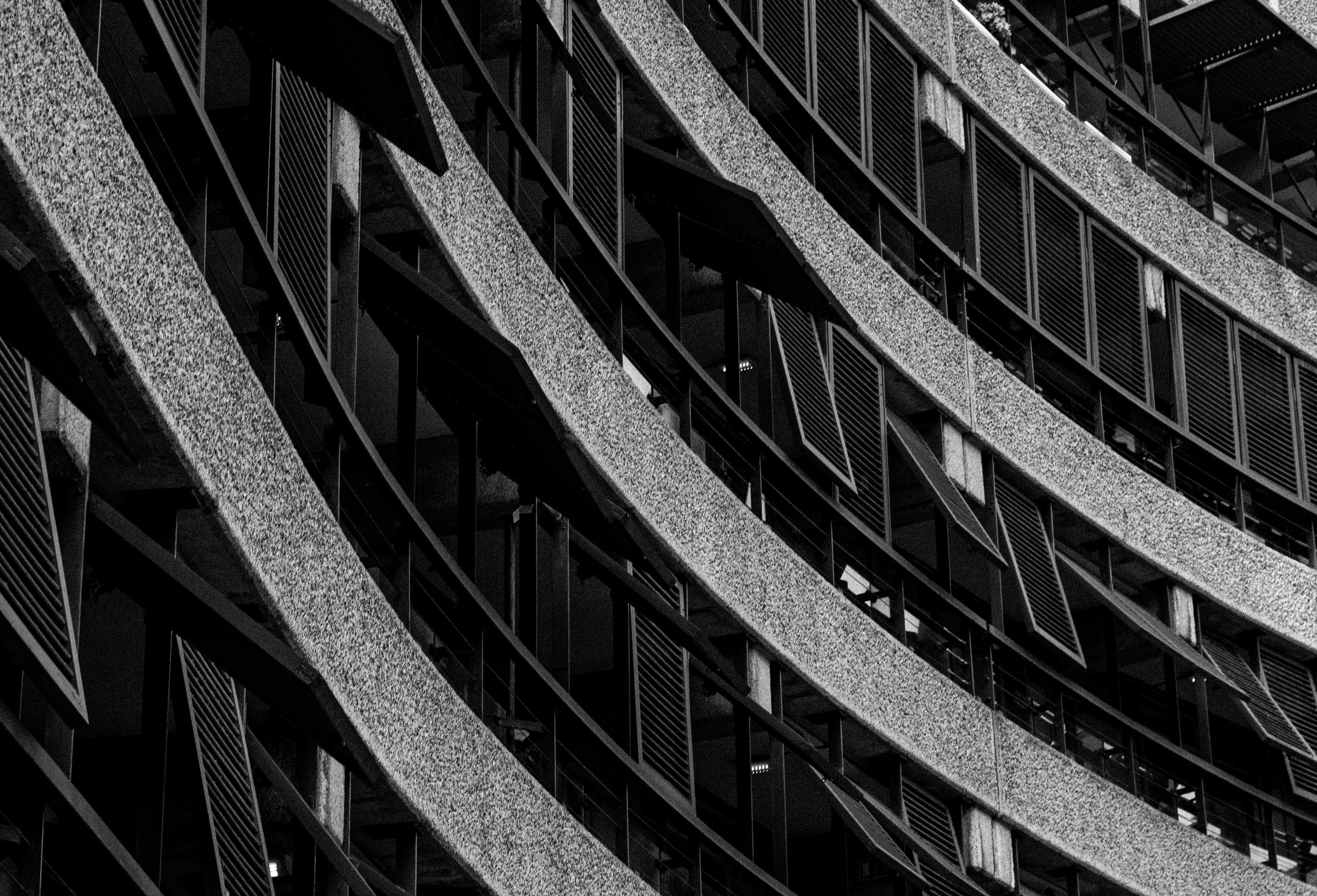 Close-up of modern building with multiple angled concrete and metal balconies in black and white.