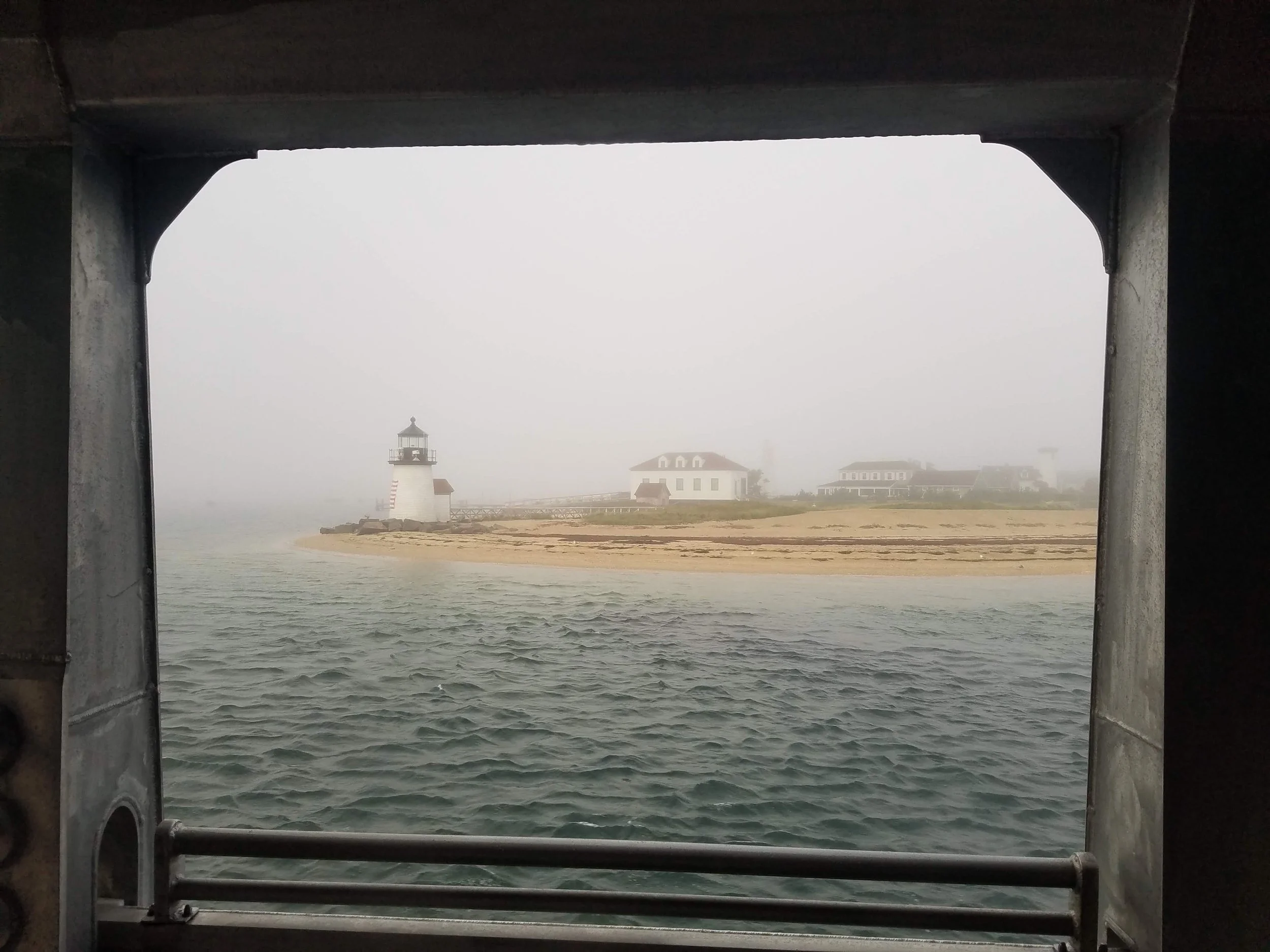 Photo of Nantucket's Brant Point Lighthouse and rippling oceah water as seen from inside the ferry.