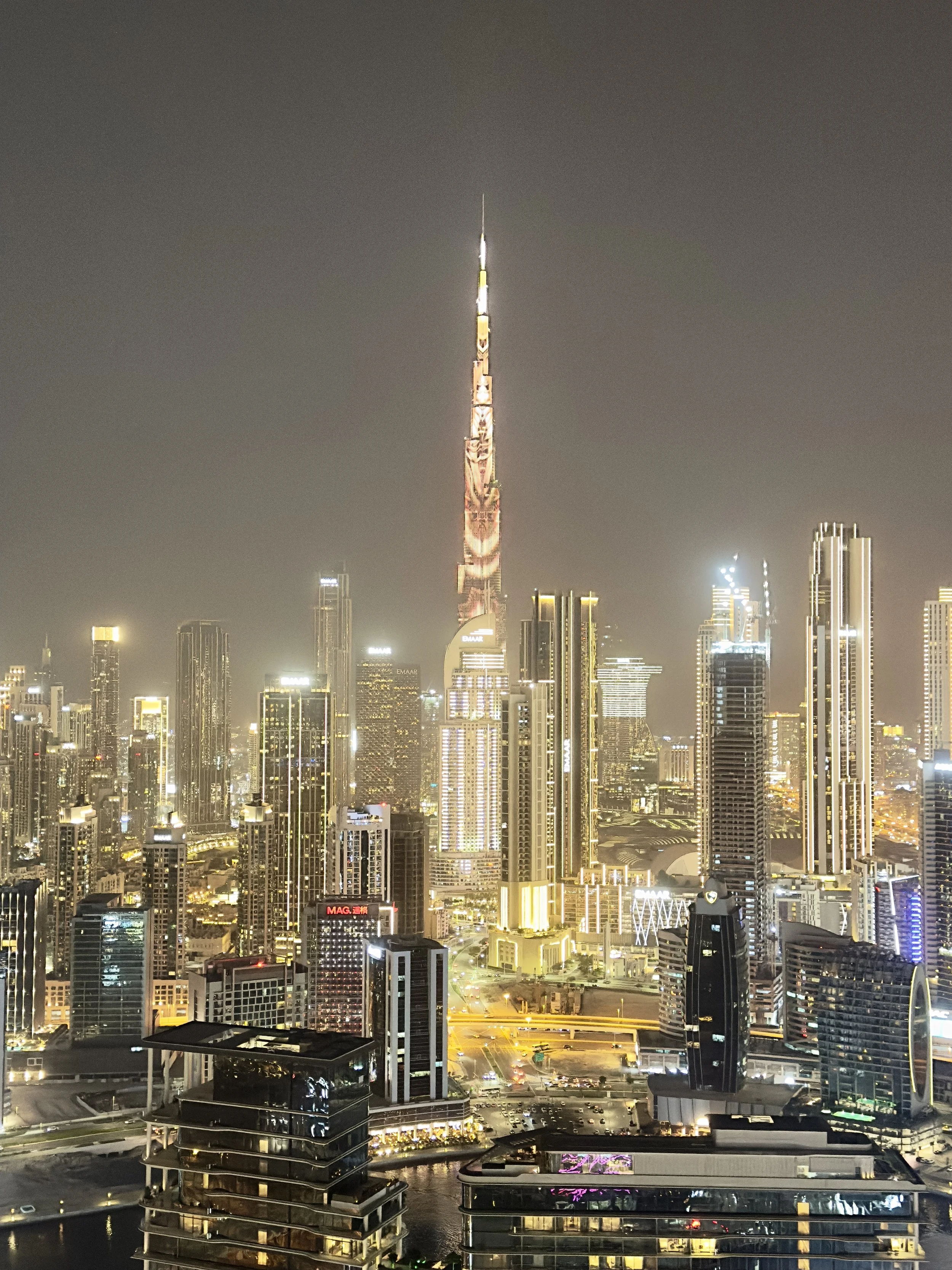 Night view of Dubai city skyline with illuminated skyscrapers, including the Burj Khalifa in the center.