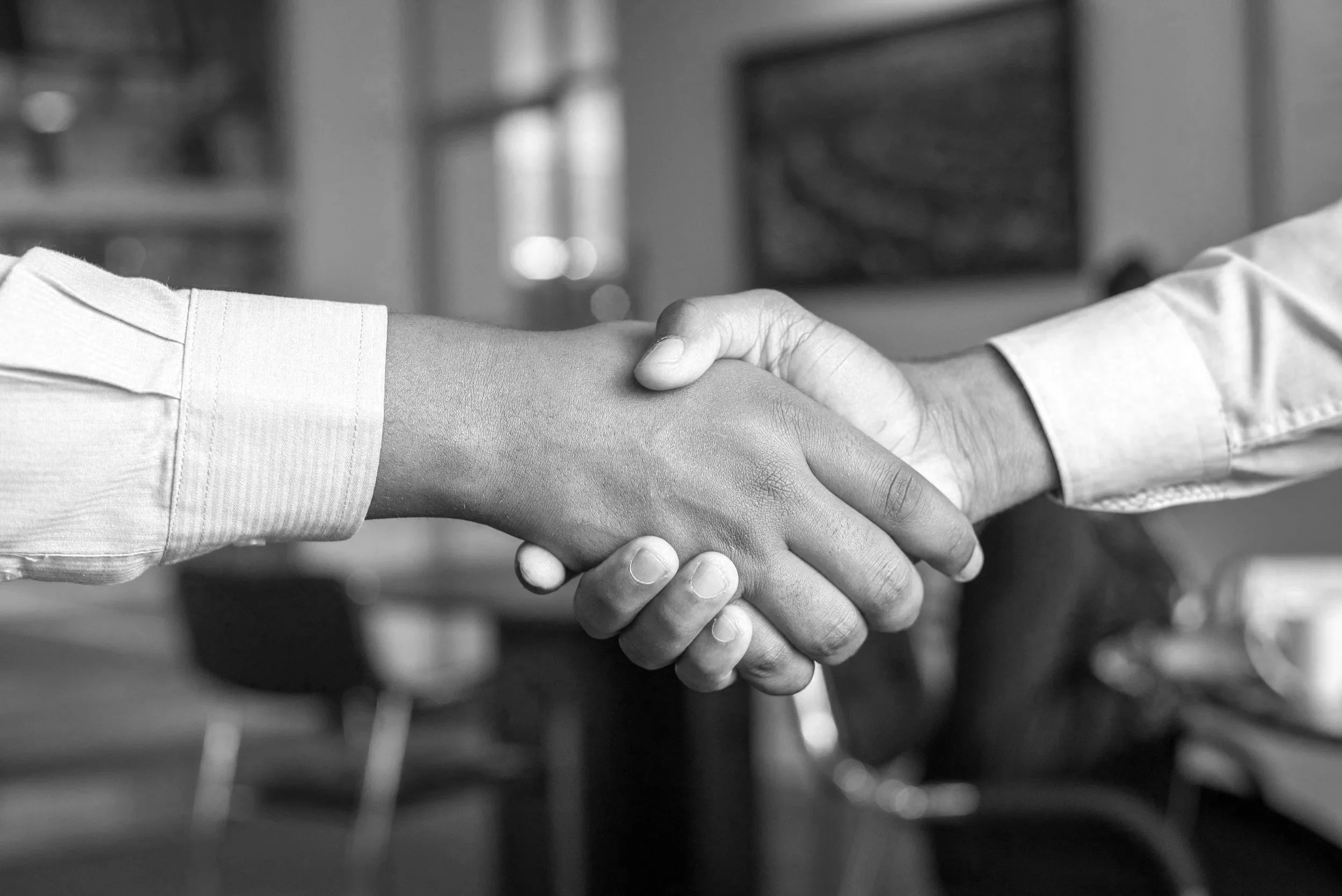 Two people shaking hands in an office setting.