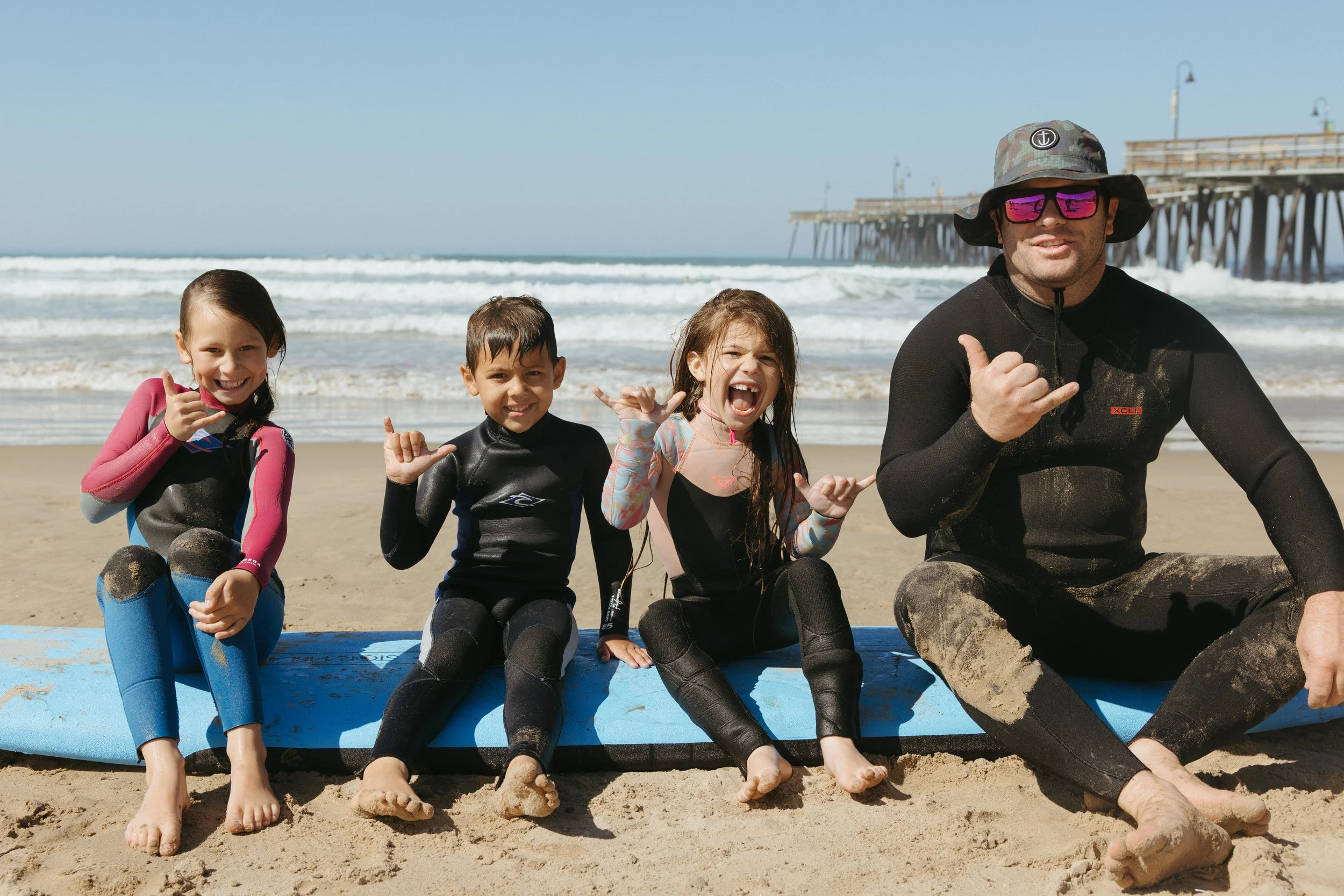 Group of young people carrying surfboards on the beach near the ocean.