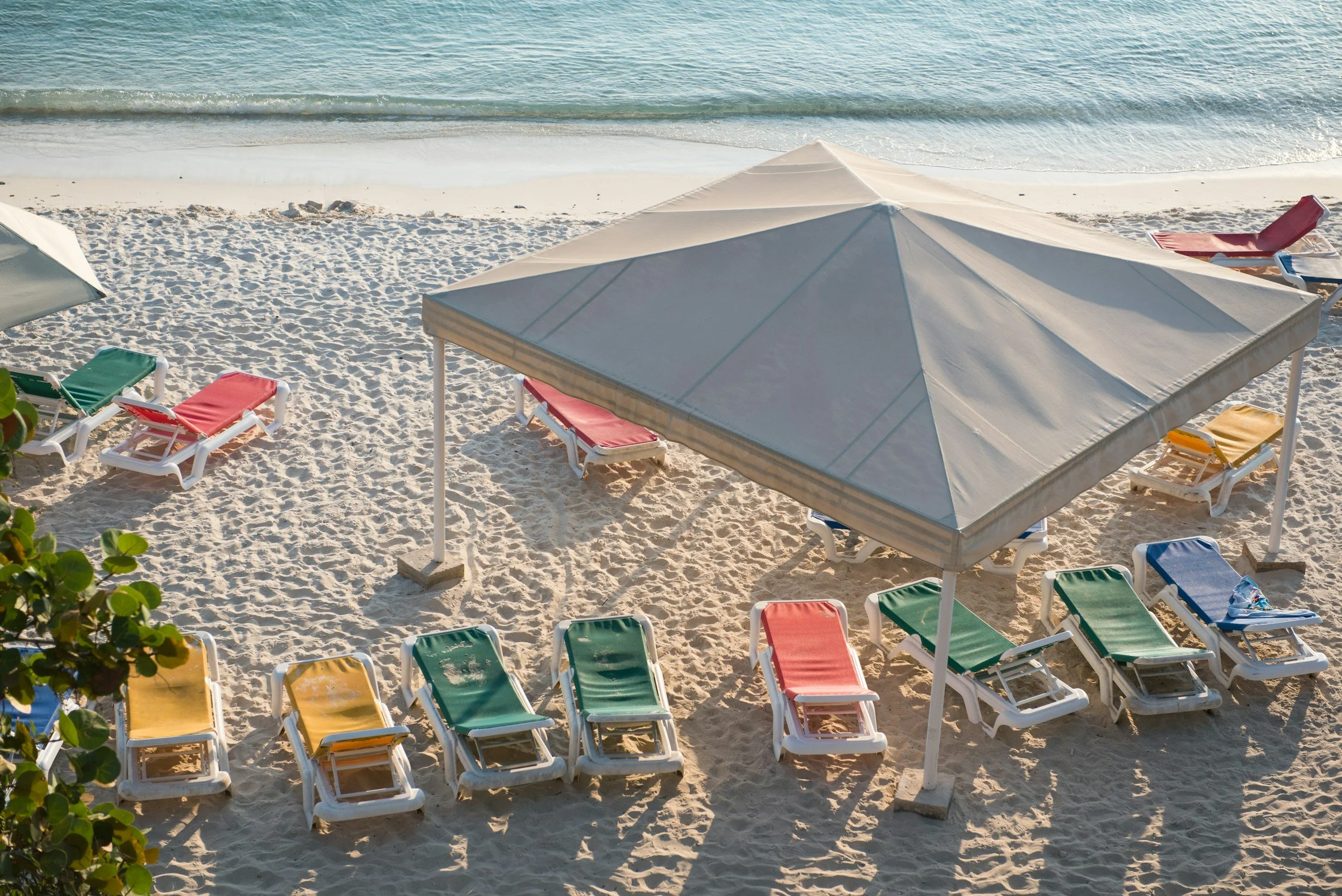 Empty beach chairs and umbrellas on sandy beach near the ocean.