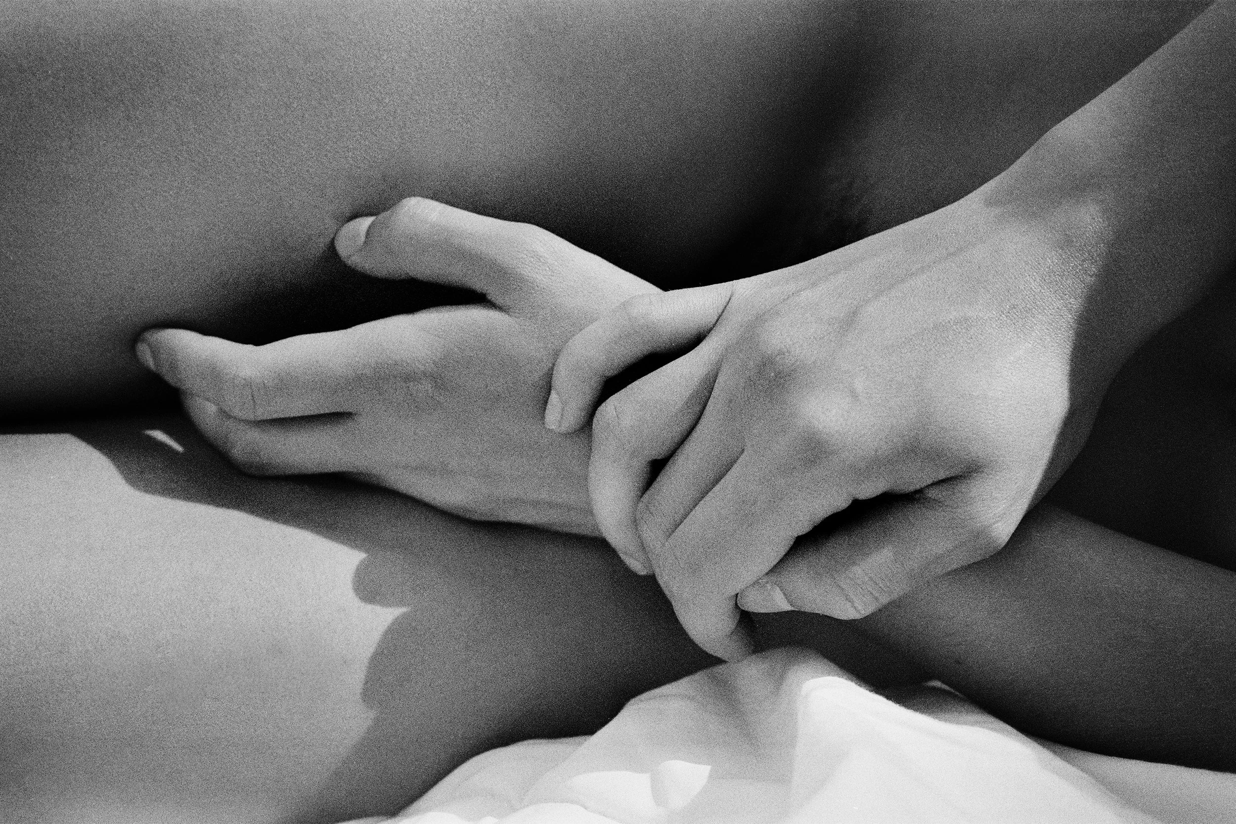 Close-up of two hands interlocked on a person's body, black and white photograph.