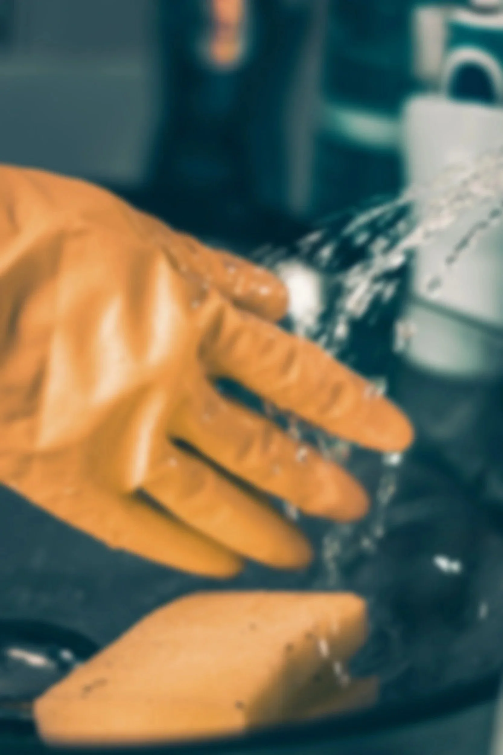 Close-up of a gloved hand reaching toward a washing machine with soap suds inside.