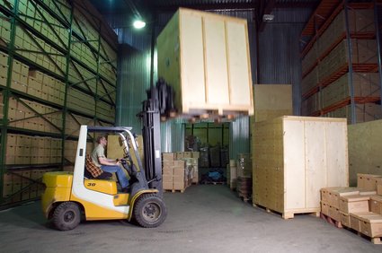 A forklift operating in a warehouse, lifting a large wooden crate.