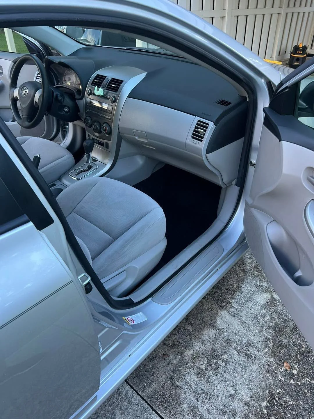 Interior of a silver car showing front seats, dashboard with controls, gear shift, and steering wheel.