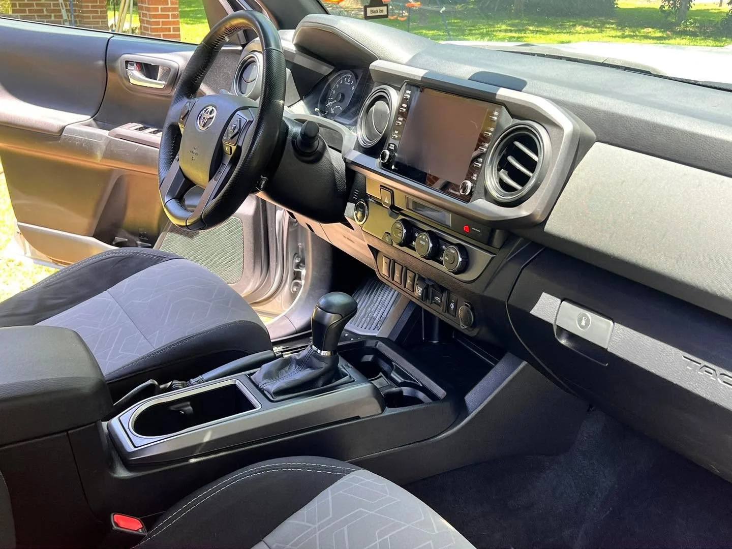 Interior of a Toyota vehicle, showing the dashboard, steering wheel, gear shift, and front seats with fabric upholstery.