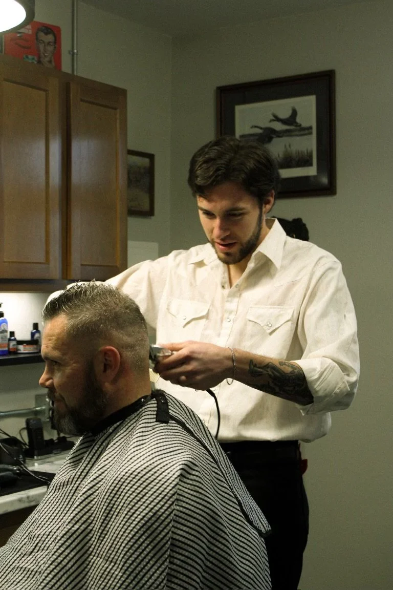 A man giving a haircut to another man in a barber shop.