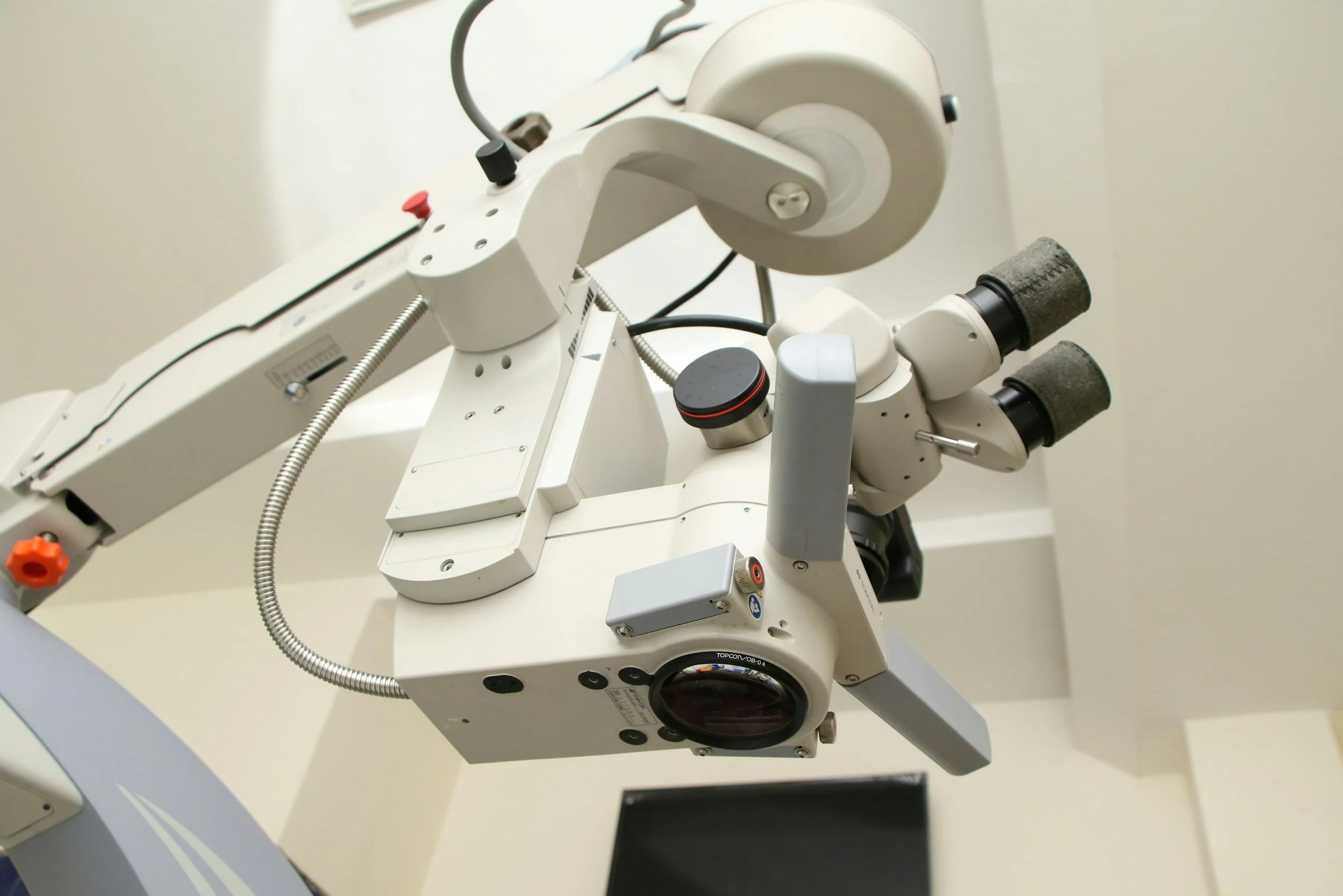 A medical surgical microscope used for eye surgery, mounted on an adjustable arm in a clinical setting.