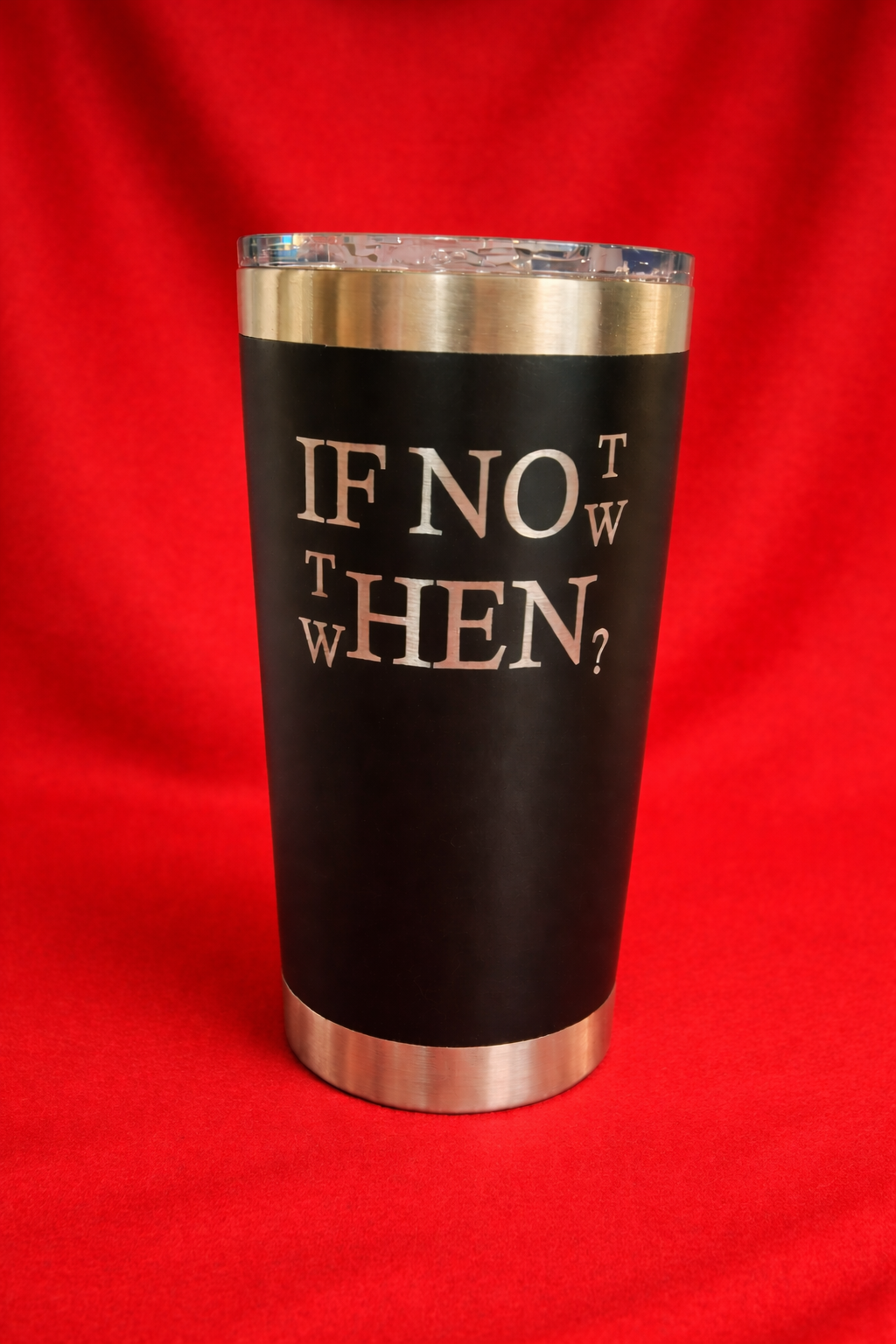 A black tumbler with a silver rim and lid, featuring the phrase "If not now, when?" in white text, set against a red background.