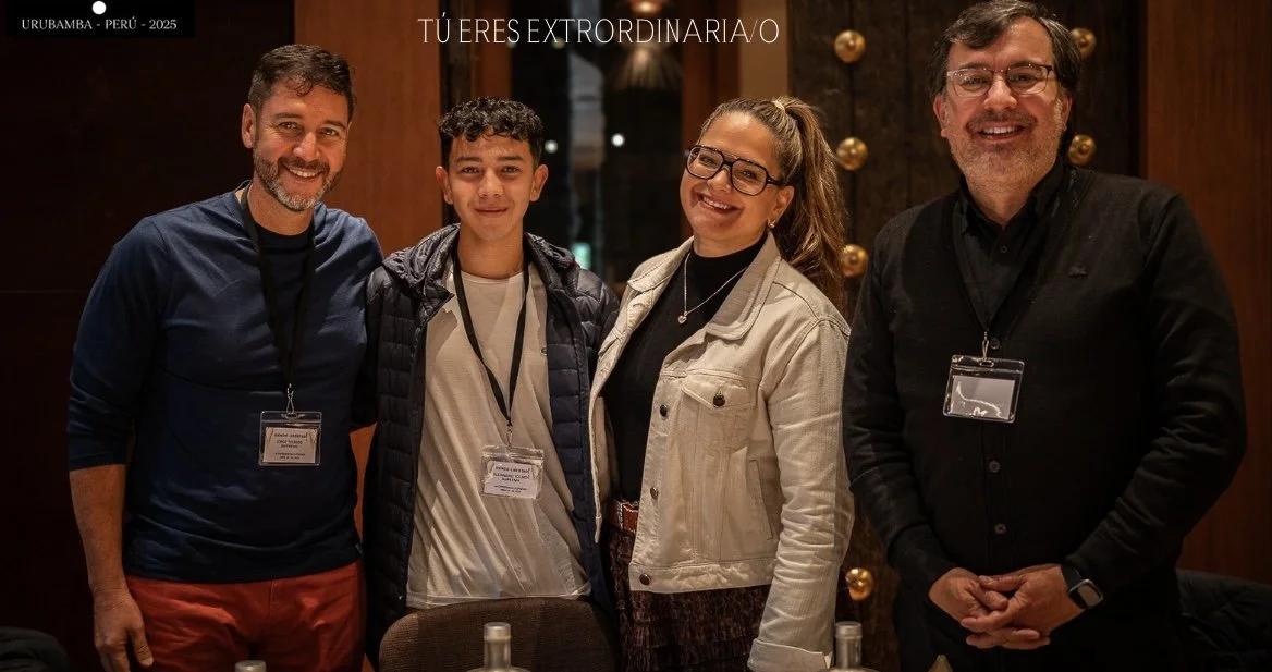 Cuatro personas sonriendo en una reunión o evento, entre ellas un joven y tres adultos, en un entorno con decoraciones doradas y madera.